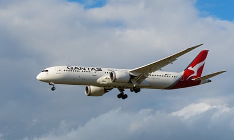 A Qantas plane flying through a cloudy sky