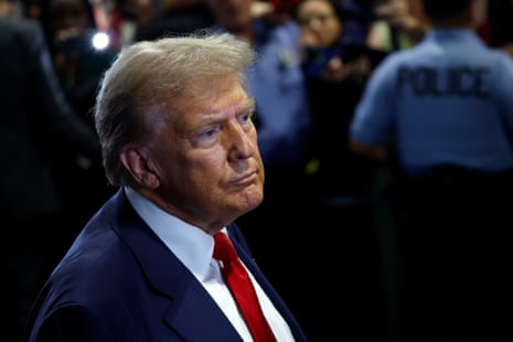 Donald Trump, wearing a blue suit and red tie, looks off to the side