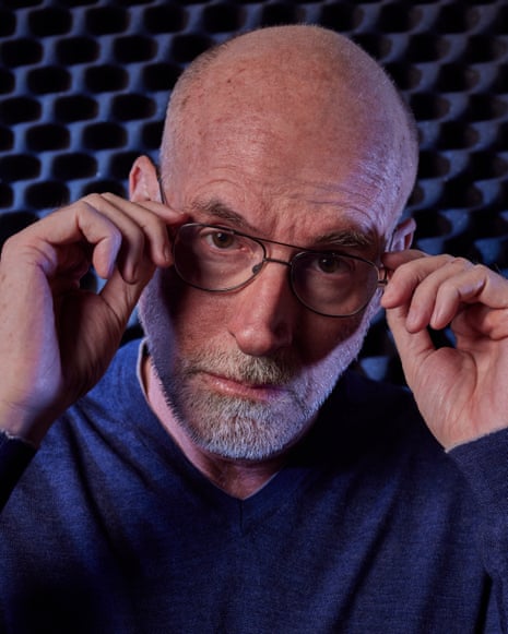 Close up picture of Scott Galloway with cropped beard, blue T-shirt and blue/black patterned background