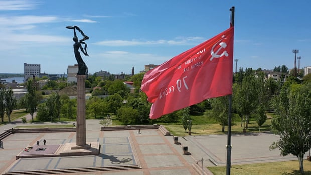 A replica of the Soviet victory flag flies next to a World War II memorial in the city of Kherson.