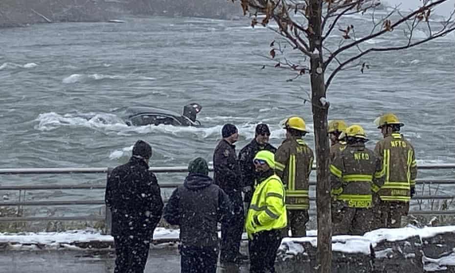 First responders monitor a car partially submerged in the Niagara River near the brink of American Falls.