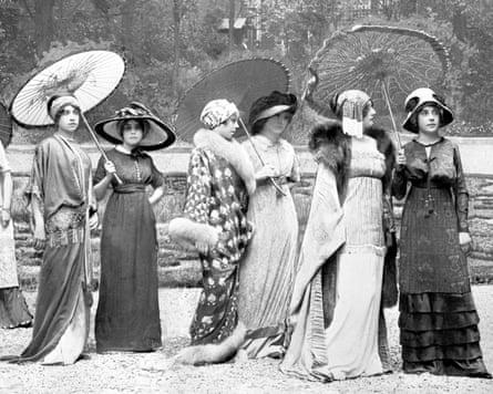 Models pose in long dresses and parasols in a park