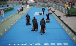 Workers during rainy weather prepare the track for the women’s triathlon at the Tokyo Olympics.