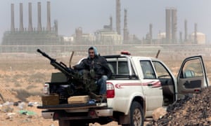 An anti-government rebel sits with an anti-aircraft weapon in front of an oil refinery in Ras Lanuf, eastern Libya.