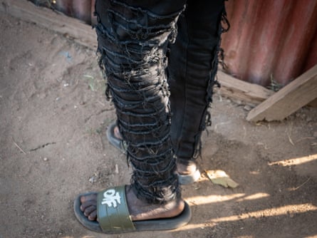 A young African man in trendily ripped jeans seen from the waste down