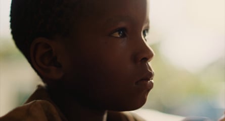A close up film still of a young boy in profile.