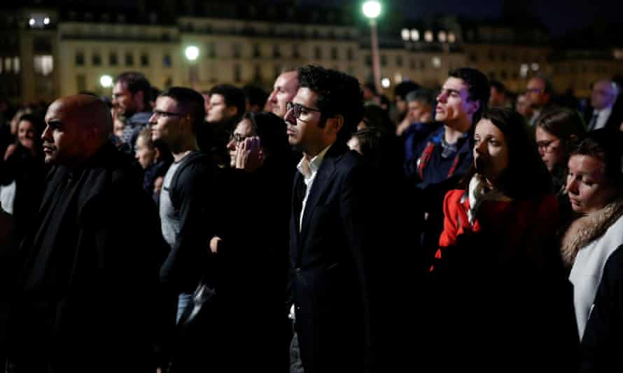 People react near the Notre Dame Cathedral after it suffered heavy damage from a fire.