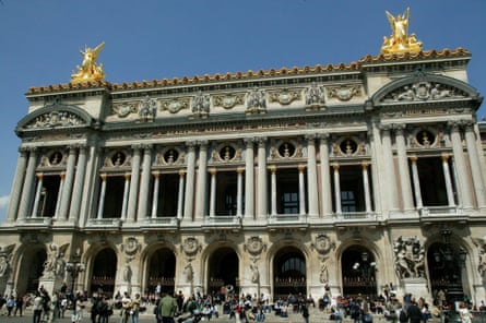 The exterior of the Palais Garnier opera house, with gold statues and columns, and crowds outside