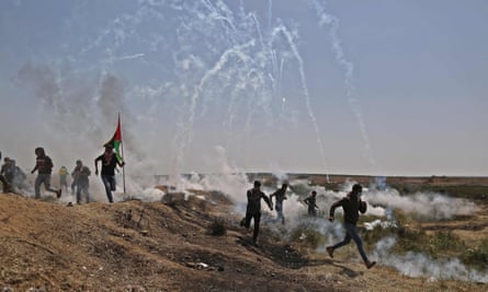 Palestinians run for cover from tears gas canisters fired at them east of Gaza City in the Gaza strip.