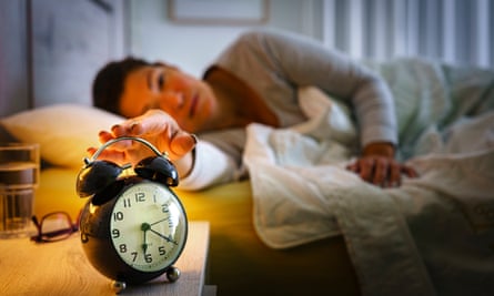 Woman in bed turning off her alarm clock early morning