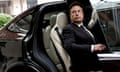 Elon Musk gets out of a dark Tesla vehicle