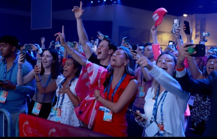 A crowd in a darkened hall cheering.