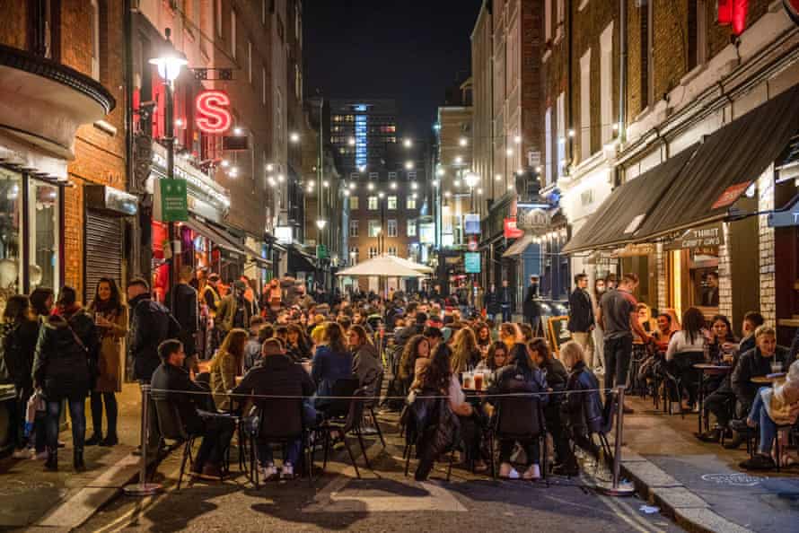 Customers eat and drink on the street outside a bar ahead of a coronavirus lockdown in the Soho