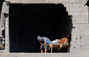 A Palestinian sitting alone with his head in his hand, leaning forward looking desolate, in a hole in the side of a wall