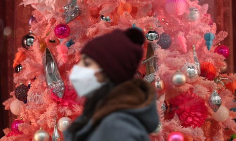 A woman walking past a Christmas tree in a store window on Oxford Street
