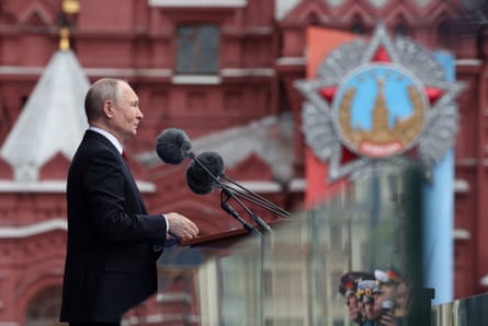 Vladimir Putin speaks on a stage in Red Square.