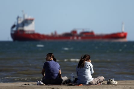 Women on a beach in front of an oil tanker near the port in Fos-sur-Mer, southern France.