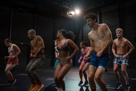 A line of dancers in grungy gym clothes jumping on the spot
