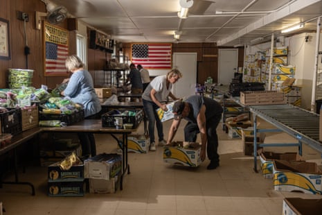 Workers at a food pantry pack up food into boxes in a storage room