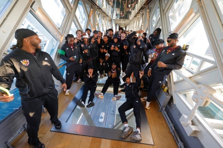 Players from the Arizona State University Sun Devils US football team pose over the glass window above Tower Bridge after a boat trip from Putney Pier to Tower Bridge.