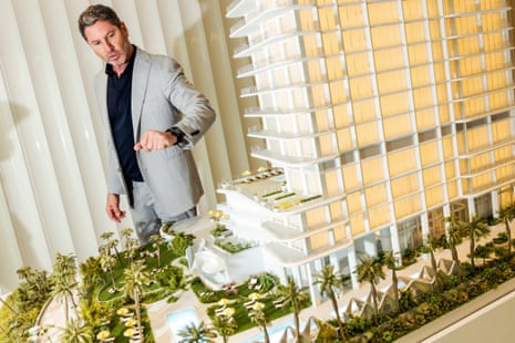 A man in a gray suit shows a condo development miniature