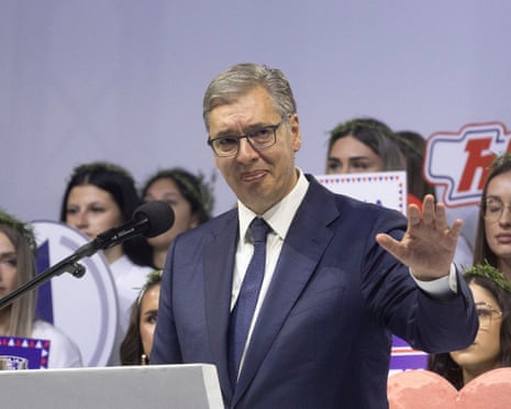 Aleksandar Vucic gestures with his hand while speaking at a rally podium microphone