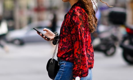 A woman walks down a street in Paris on her mobile phone.
