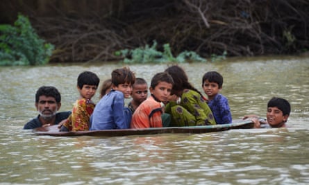 A man (L) along with a youth use a satellite dish to move children across a flooded area after heavy monsoon rainfalls in Jaffarabad district, Balochistan province, on 26 August