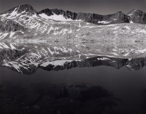 Black and white photo of a snowy mountain reflected in a lake.