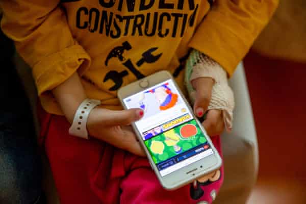 Three-year-old Mila Ustenko plays on a phone at the Motol hospital in Prague where she has had surgery on a throat abscess.