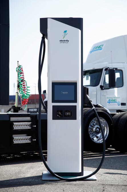 A white vehicle charging station can be seen in front of a white semi truck.