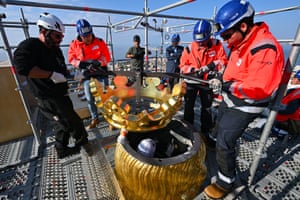 Technicians on scaffolding lower a restored golden crown on to a Virgin Mary statue