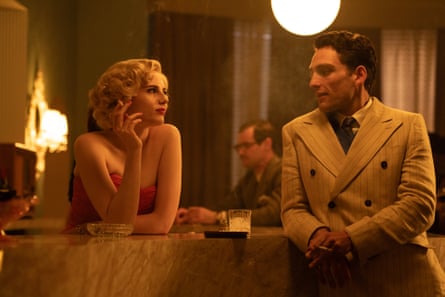 Two actors in 1950s clothes stood chatting at a bar
