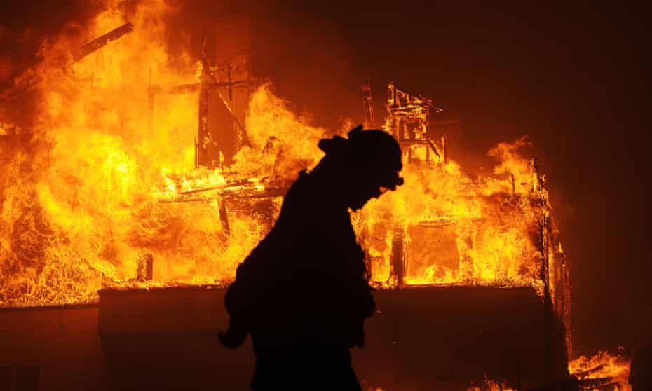 A fireman walks past a burning house in Ventura, California. Wildfires in the state have been made more violent by a cycle of drought and heavy rainfall.