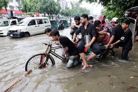 People try to push a bicycle through floodwaters in Dhaka, Bangladesh.