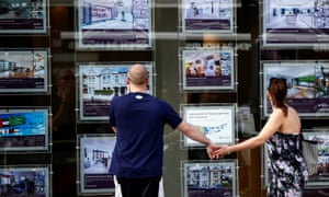 A couple look in an estate agent’s window.