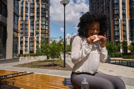 Woman sitting on a bench eating a sandwich.