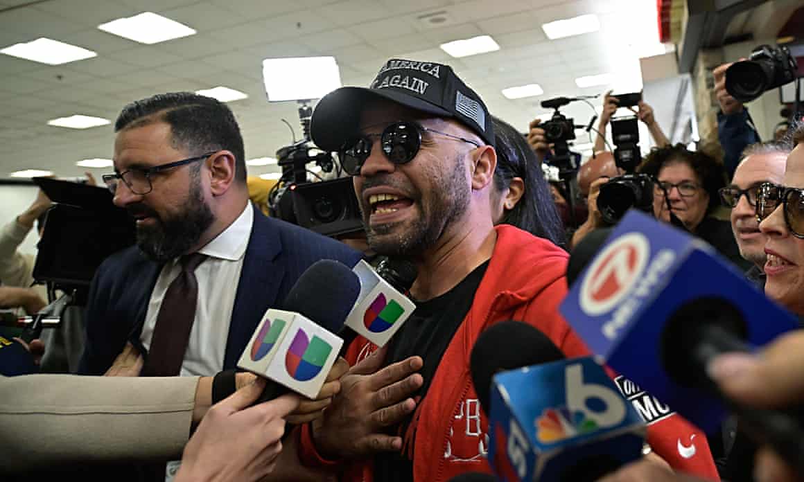 Man with cap in crowd speaking to mic