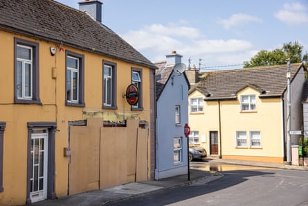Yellow-painted pub building looking near-abandoned and dilapidated, with doors and windows boarded up.