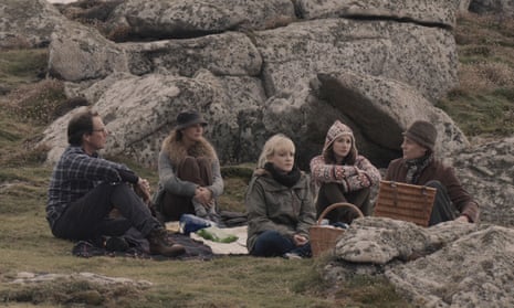 five middle class people having a sunless picnic by some rocks, no one talking to anyone else