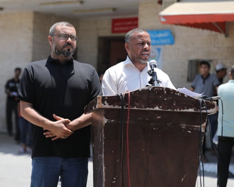 The pair stand at a worn wooden podium with a microphone during an outdoor press conference