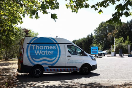 A Thames Water van is parked under a tree in a car park.