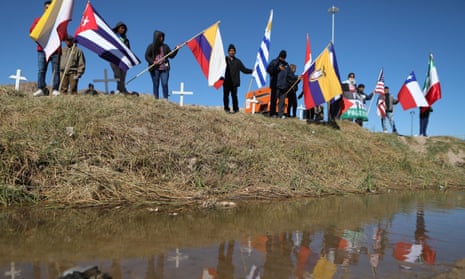 Migrants seeking asylum in the United States through the CBP One digital application wave flags during a binational mass to remember migrants who have died attempting to reach the US, on the banks of the Rio Grande in Ciudad Juarez, Chihuahua State, Mexico, on November 9, 2024.