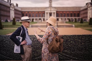 Two people talk, one gesticulating, in front of a building