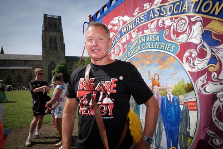 Guy poses for a picture with a Durham Miners’ Association banner in the backgroun