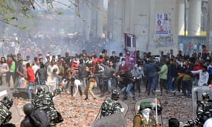 Protesters throw stones at police in eastern Delhi on Monday. Five people died in violence across the capital.