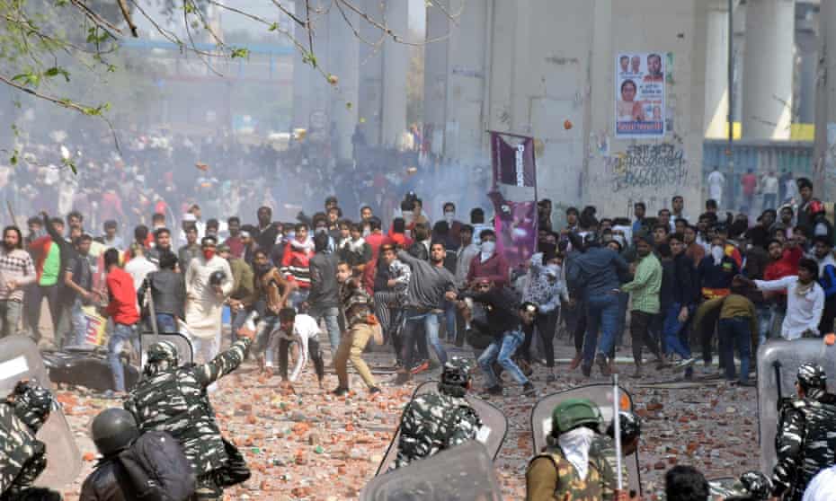 Protesters throw stones at police in eastern Delhi on Monday. Five people died in violence across the capital.