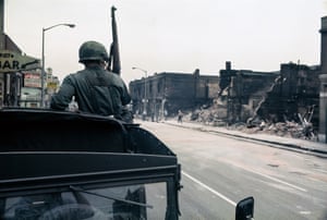A National Guardsman stands watch in front of buildings reduced to rubble