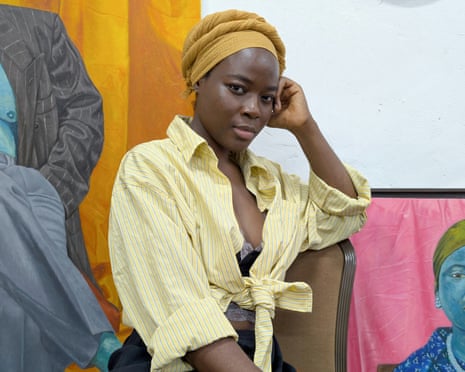 Hawa Awanle Ayiboro with two paintings of women with blue skin wearing suit jackets
