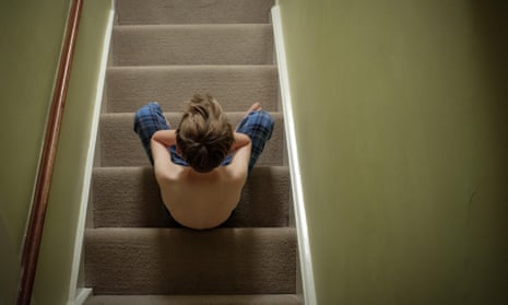 A child sitting on the stairs with his head in his hands looking upset
